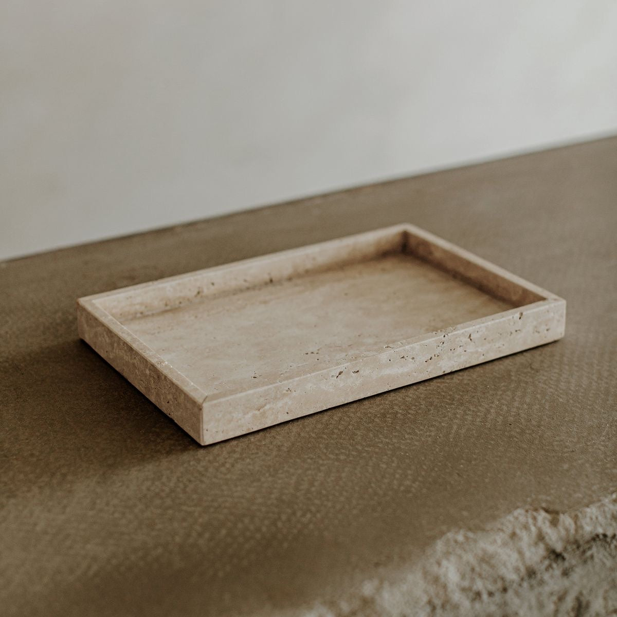A beige Travertine marble tray placed on a surface with a neutral background.